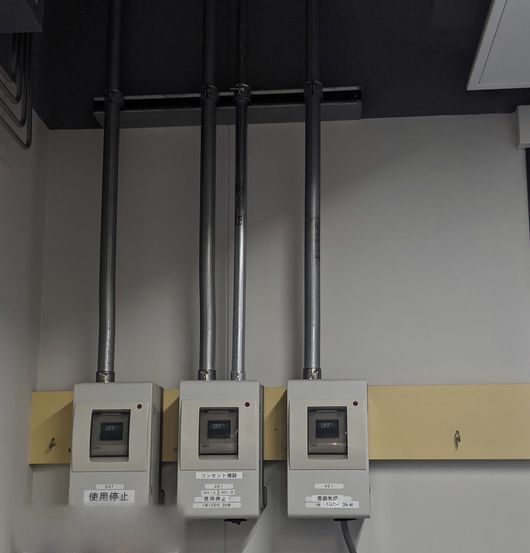 壁に並べて取り付けたブレーカーボックスと、天井から下ろした電線管